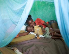Au Ghana, mère et fils, Mercy et Daniel, s’accouchent sous une moustiquaire imprégnée d’insecticide qu’ils ont reçue pour leur protéger du paludisme.